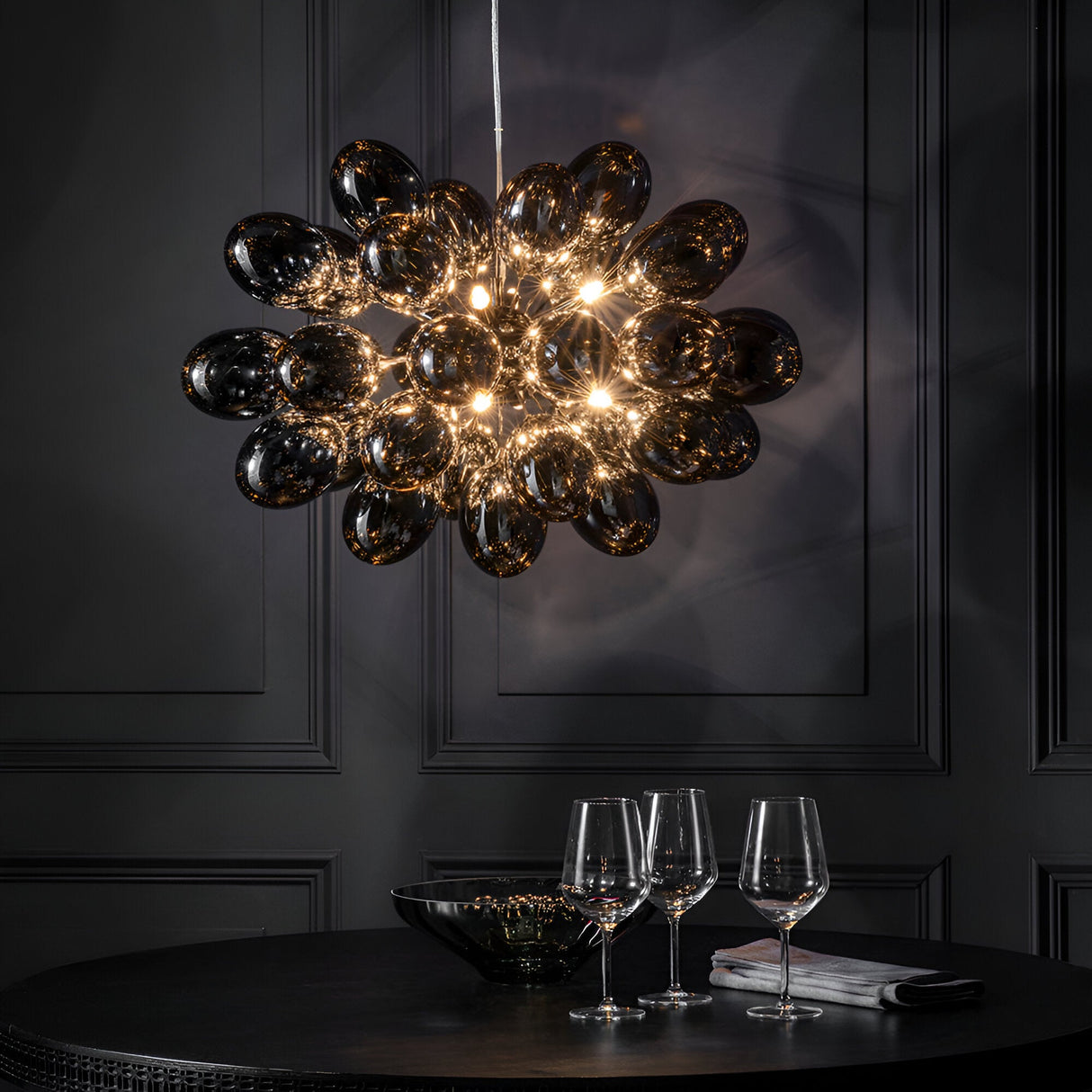 Endon Brenworth 8 light pendant in black chrome with clustered dark chrome glass globe shades, hung above a dining table with wine glasses.