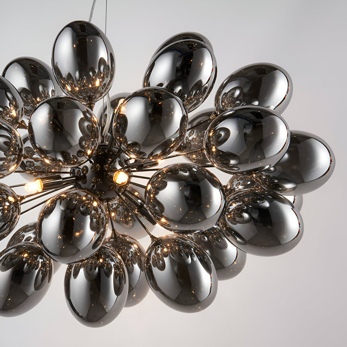Endon Brenworth 8 light pendant with cluster of electro-plated dark chrome glass globe shades on a black chrome sputnik frame, shown against a pale background.