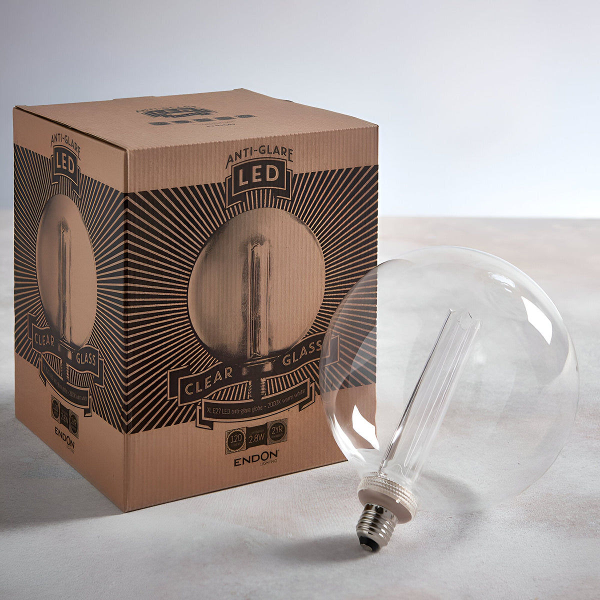 Endon 2.8W E27 LED clear globe bulb lying beside its printed kraft retail box on a light neutral surface.