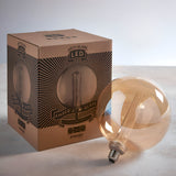 Endon 2.8W E27 LED amber globe bulb with etched acrylic filament sleeve, shown beside its printed cardboard packaging on a neutral surface.