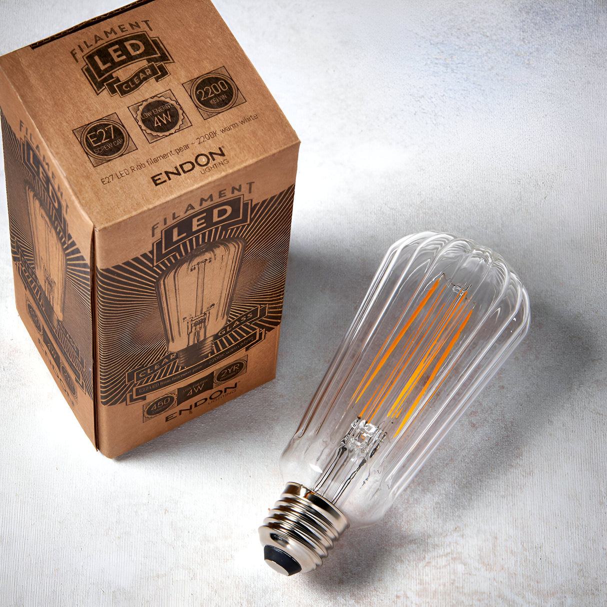 Endon 4W E27 LED filament pear bulb with ribbed clear glass and warm white filament, shown beside its printed kraft box on a light background.