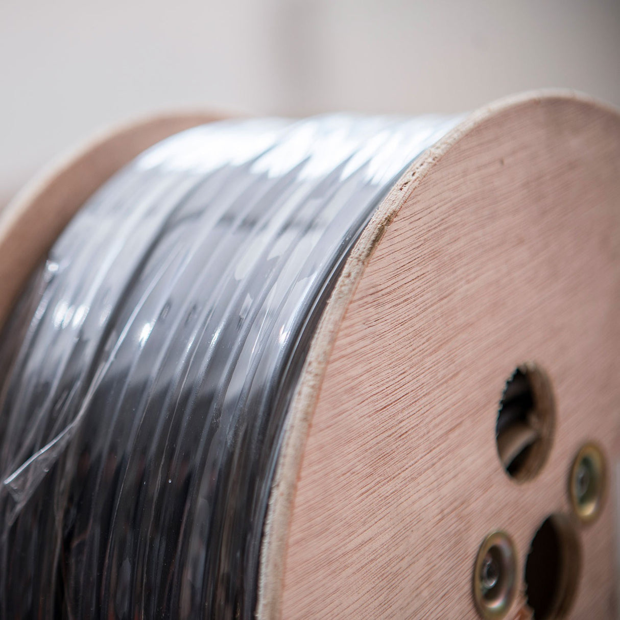 Close-up of the AVSL Mercury 100V line speaker cable on a wooden 100m reel, showing black PVC-sheathed cable wound tightly around the spool.