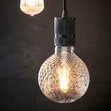 Endon 4W E27 LED filament faceted globe bulb in clear glass with warm white glow, suspended from a knurled matte black pendant fitting.