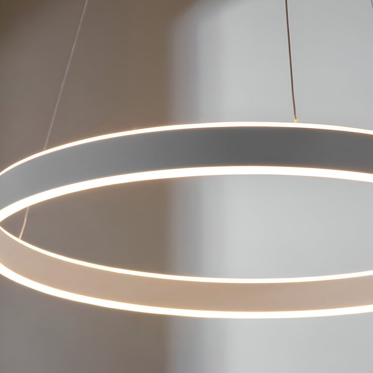 Bramford Pendant in nickel and white, a large circular ring fixture on thin cables with a glowing frosted edge, shown close-up against a soft grey background.