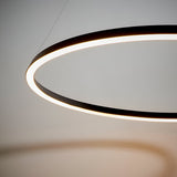 Cliffton LED Pendant in black and white, a large circular ring fixture with a glowing white diffuser, suspended by fine cables against a light grey background.