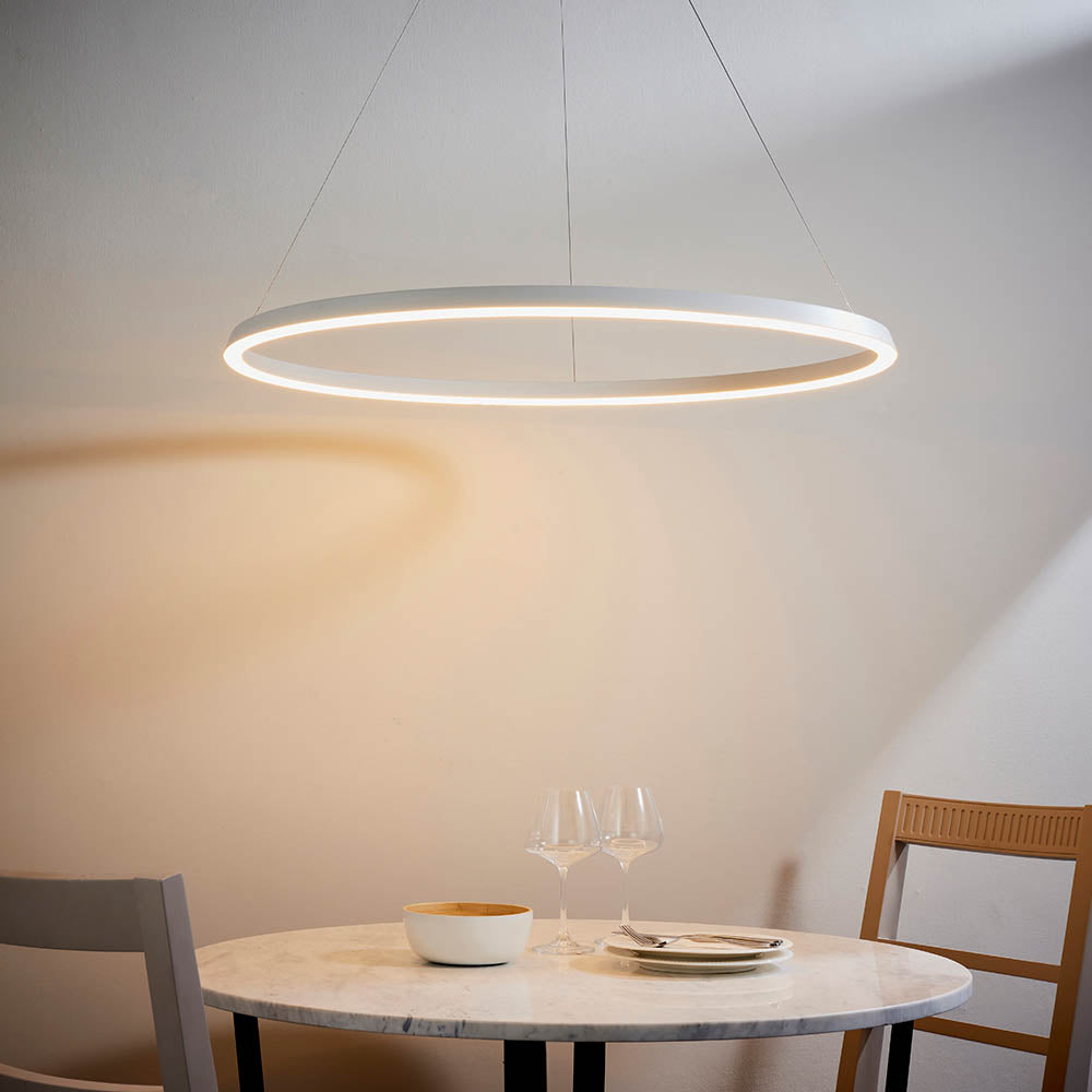 Endon Cliffton LED pendant in white, a large slim ring suspended by fine wires above a round marble dining table with glasses and chairs.