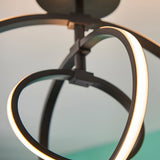 Close-up of Endon Corso semi-flush ceiling light showing intertwined matt black metal loops with integrated warm white LED strips along the inner edges.
