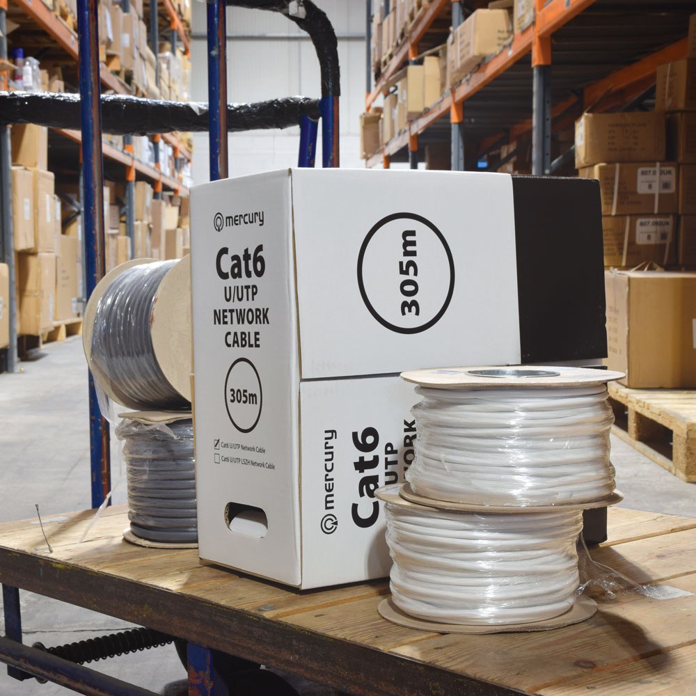 Mercury Cat6 U/UTP 305m network cable in a grey and white dispensing box on a wooden trolley beside grey and white cable reels in a warehouse.