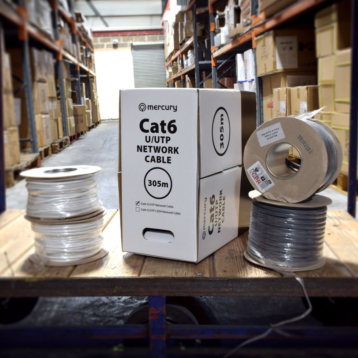 Mercury Cat6 U/UTP 305m network cable dispensing box beside grey and white cable reels on a warehouse pallet.