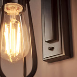 Close-up of Endon Camden wall light showing exposed E27 filament bulb in clear glass and matt black bracket with toggle switch and knurled detail.