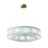 The Arvello 12 Light Layered Panel Alabaster Chandelier features soft white alabaster panels in a circular design, suspended by slim wires from a brass mount for a modern look.