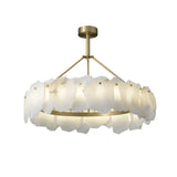 The Marvion LED Medium Petal Alabaster Chandelier features a brass frame and soft white, petal-shaped alabaster panels in a circular design, creating sculptural lighting suspended from the ceiling by a central rod.