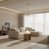 A modern living room with a white sectional, minimalist wooden furniture, and abstract art on a low console features the Aurelior LED Small Ribbed Alabaster Table Lamp – Soft White, casting a gentle glow over the neutral rug and sheer-curtained windows.