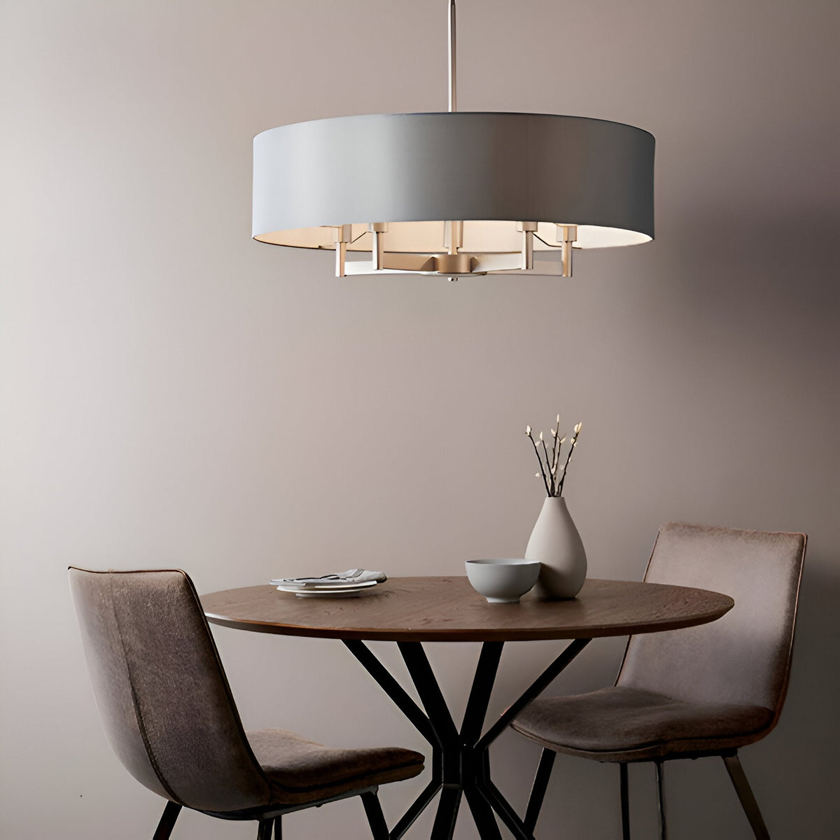 Endon Bramstead 5 light pendant with grey fabric drum shade and matt nickel frame above a round wooden dining table with two chairs.