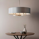 Endon Bramstead 5 light pendant with a wide grey fabric drum shade on a matt nickel frame, hanging above a round wooden table with a vase and bowl.
