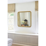 Diva Beaded Gold Frame Square Wall Mirror 95cm on a light bedroom wall, reflecting a lamp and side table, with a beaded gold metal frame around the glass.