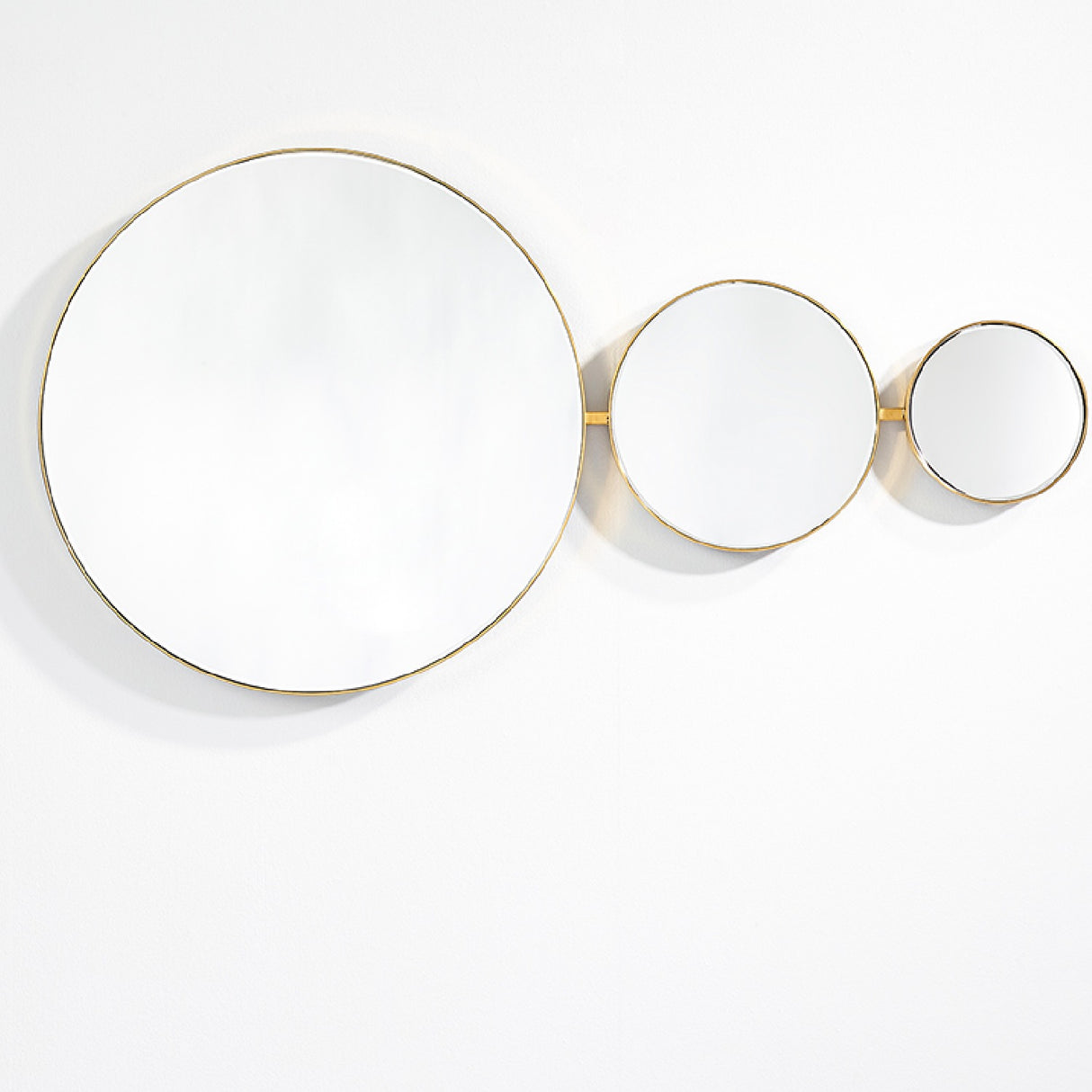 Opera Three Circle Gold Rimmed Wall Mirror 119cm shown in a horizontal arrangement of three joined round mirrors in decreasing size with thin gold frames, set against a plain white background.