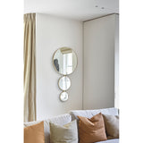 Opera Three Circle Gold Rimmed Wall Mirror 119cm featuring three joined circular mirrors in decreasing size, mounted on a light living room wall above a sofa with cushions.