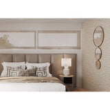 Opera Three Circle Gold Rimmed Wall Mirror, 119cm, mounted on a textured wall in a bedroom above a bedside table with lamp and upholstered headboard.