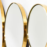 Close-up of the Opera Three Circle Gold Rimmed Wall Mirror, showing overlapping circular mirrors with polished gold rims against a white wall.