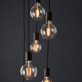Marlowe 6 Light Pendant in matt black, showing globe bulbs on staggered black fabric flex drops with matt black fittings against a dark background.