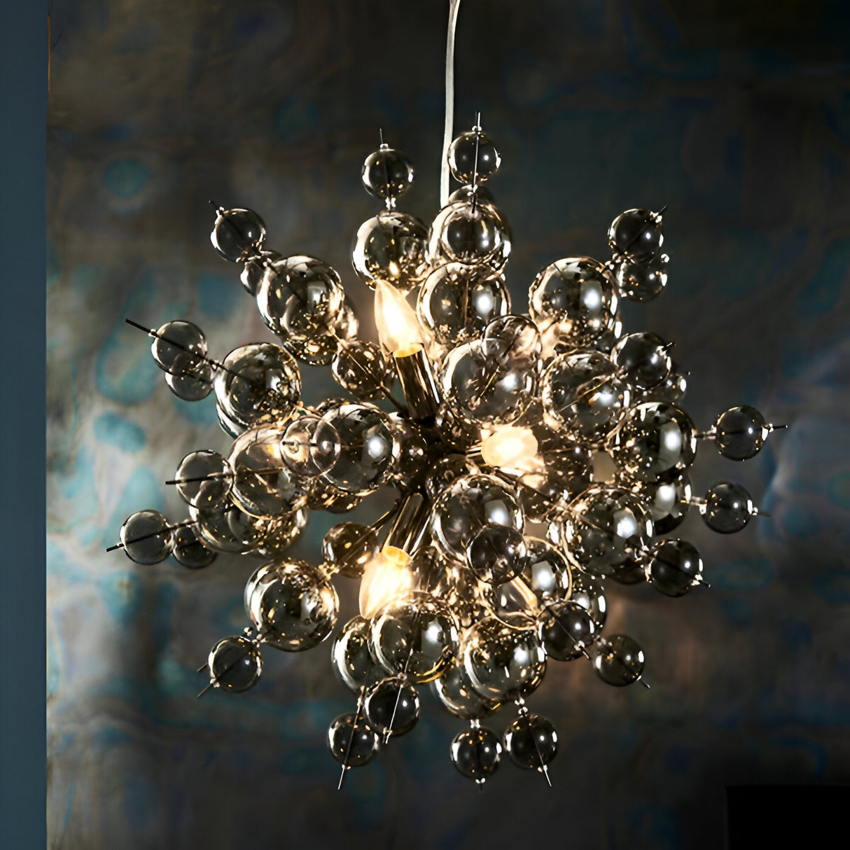 Brockford 9-light cluster pendant in black with smoked mirror and tinted glass spheres on plated metalwork, glowing against a dark textured backdrop.