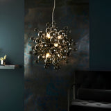 Brockford 9 Light Cluster Pendant in black, clustered smoked glass spheres on metal fittings, glowing above a dark, moody living room setting.