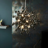 Brockford 9 Light Cluster Pendant in black, smoked glass spheres on black metal fittings, shown hanging in a moody dining room setting.