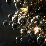 Close-up of the Brockford 9 Light Cluster Pendant in black with clustered smoked and clear glass spheres on plated metalwork and glowing E14 lamps.