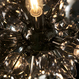 Close-up of the Brockford 9 Light Cluster Pendant in black, showing smoked glass spheres on plated metalwork with a glowing E14 bulb at centre.