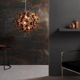 Endon Brockford 9 Light Cluster Pendant in copper with smoked mirror and tinted glass spheres, lit above a side table beside a dark textured wall.