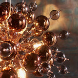 Endon Brockford 9 Light Cluster Pendant in copper, close-up of smoked mirror and tinted glass spheres on plated metalwork with warm glowing lamps.