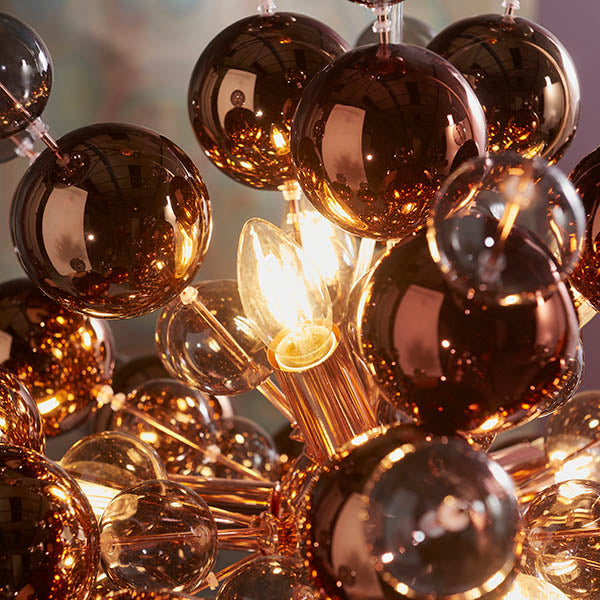 Endon Brockford 9 Light Cluster Pendant in copper, close-up of tinted mirrored glass spheres around a lit E14 candle bulb on plated metalwork.