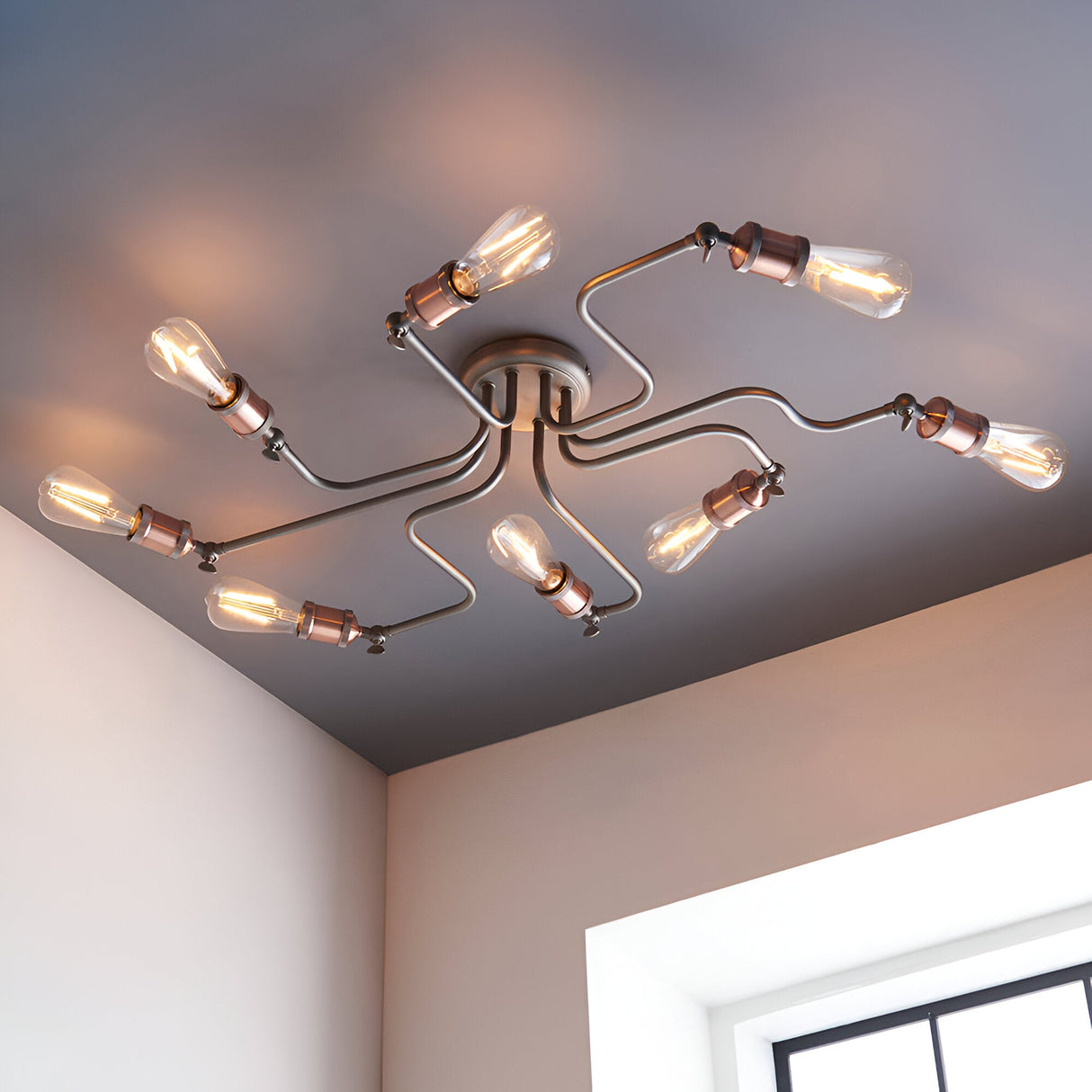Brackley 8 Light Semi-Flush Ceiling Light in pewter metal finish with copper-toned fittings and exposed bulbs, shown angled across a bedroom ceiling.