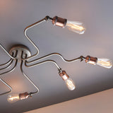Brackley 8 Light Semi-Flush Ceiling Light in pewter, metal arms with copper-toned E27 bulb holders extending across a plain grey ceiling.