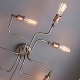 Brackley 8 Light Semi-Flush Ceiling Light in pewter finish, close-up of angled metal arms with copper-tone lamp holders and exposed E27 filament bulbs.