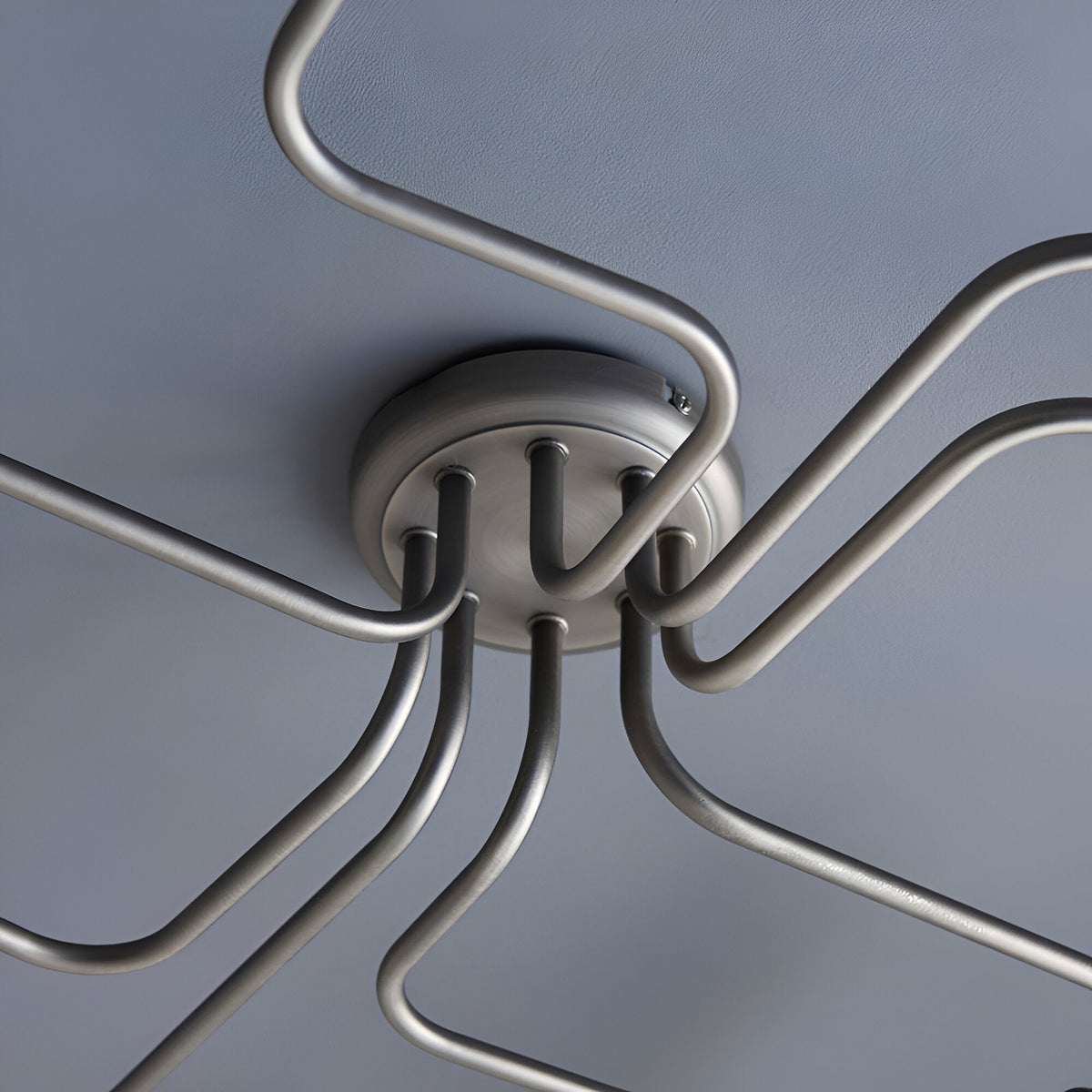 Close-up of the Brackley 8 Light Semi-Flush Ceiling Light in pewter, showing metal arms with E27 fittings meeting at a round ceiling plate.
