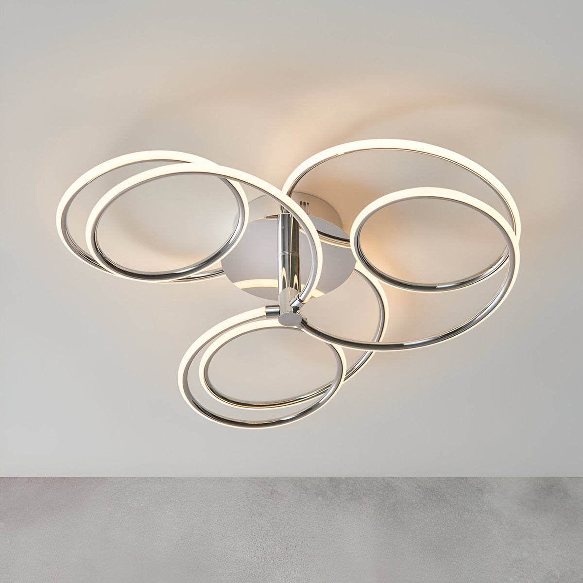 Endon Ravel LED semi-flush ceiling light in chrome, featuring five interlinked illuminated rings in a sculptural cluster against a plain light background.
