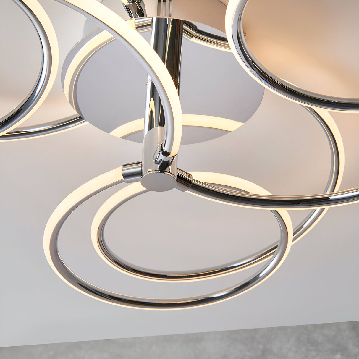 Close-up of the Endon Ravel LED semi-flush ceiling light in chrome, showing interlinked illuminated rings around a central polished chrome hub.