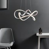 Endon Crancombe LED pendant light in matt white with a sculptural looped ribbon form on clear wires, styled above a grey chair and side table.