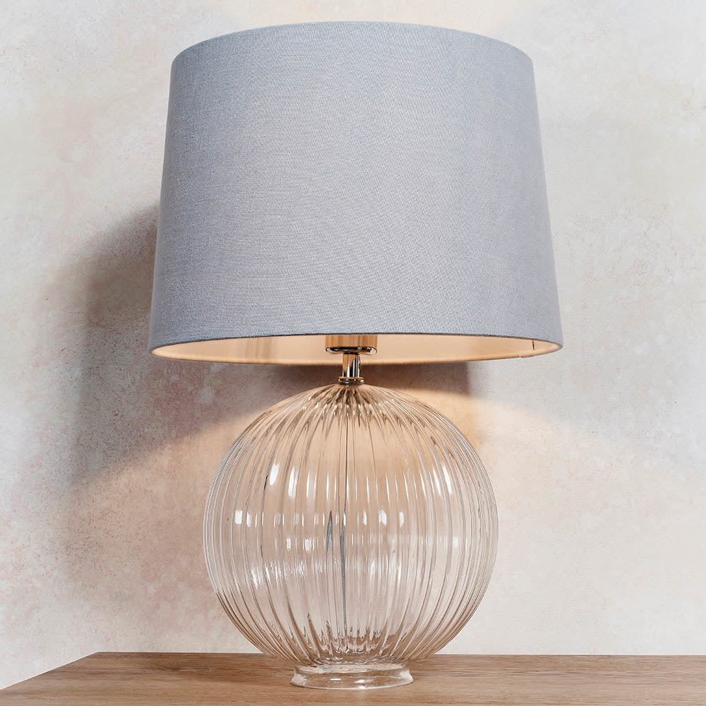 Endon Brockdale table lamp with a clear ribbed glass globe base, satin nickel detailing, and tapered grey fabric shade on a light neutral background.