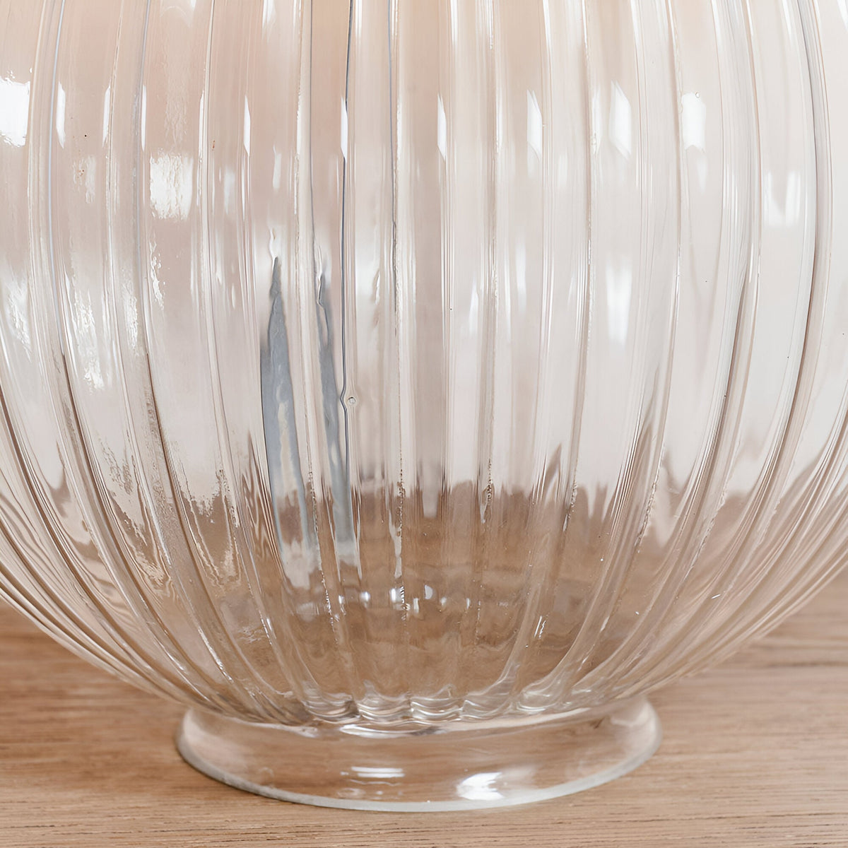 Close-up of the Endon Brockdale table lamp base showing the clear ribbed glass column and clear glass foot on a light wood surface.