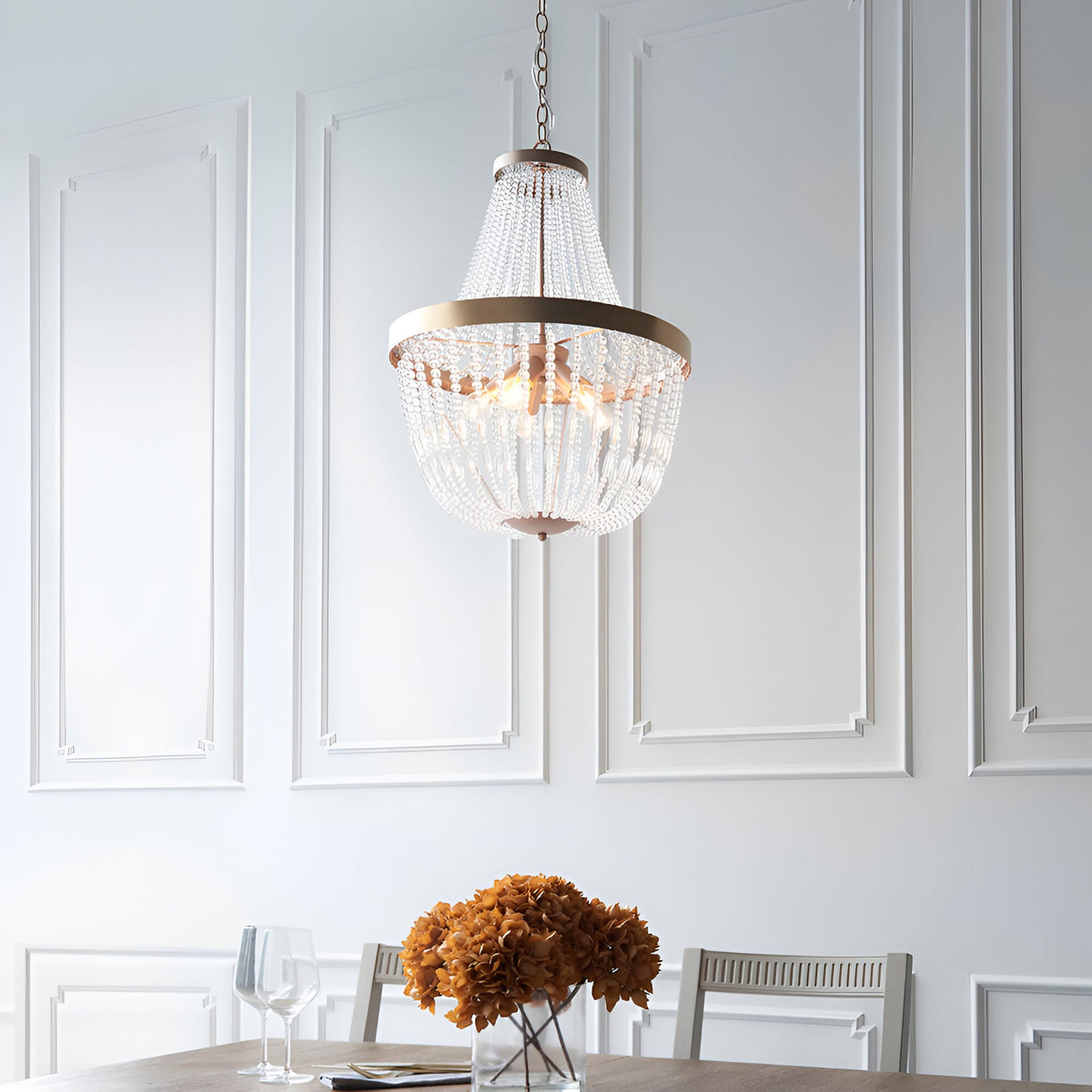 Bevdale 5 Light Pendant in gold, tiered glass bead chandelier-style design, hung above a dining table in a panelled white-walled room.