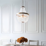 Bevdale 5 Light Pendant in gold, tiered glass bead chandelier-style design, hung above a dining table in a panelled white-walled room.