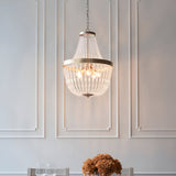 Bevdale 5 Light Pendant in gold, tiered chandelier-style fixture with clear glass beads, hung above a dining table on a panelled white wall.