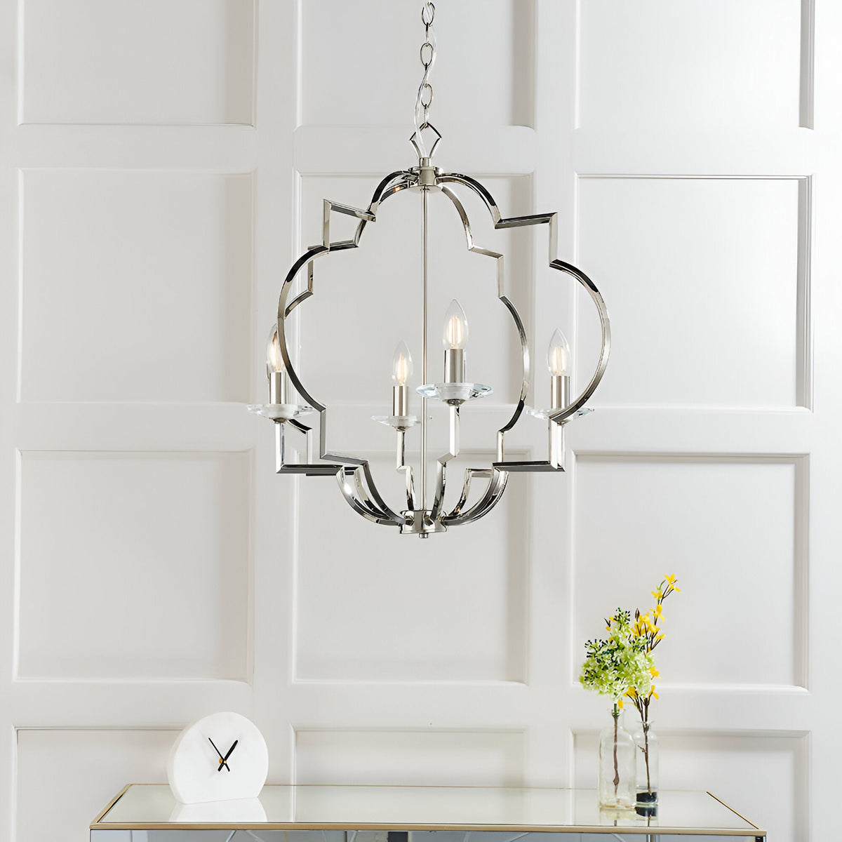 Bramfield 4 Light Pendant in polished nickel with quatrefoil frame and crystal bobeches, hung on a chain above a mirrored console in a light-panelled room.