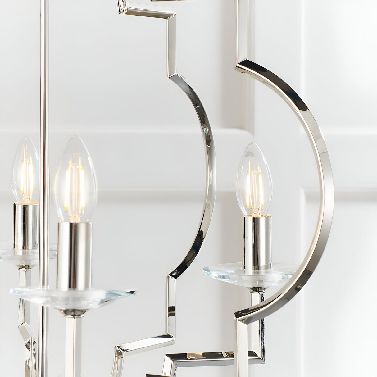 Close-up of the Bramfield 4 Light Pendant in polished nickel, showing candle bulbs on glass bobeches with curved metal arms against a white background.