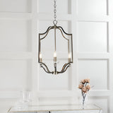 Endon Caldbourne 4 light pendant in antique brass with curved frame and crystal bobeches, hung on chain above a mirrored console in a panelled room.