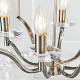Close-up of Endon Caldbourne 4 light pendant showing antique brass candle-style lampholders with clear K5 crystal bobeches and lit filament bulbs.