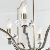 Close-up of Endon Caldbourne 4 light pendant showing antique brass candle holders, clear K5 crystal bobeches and lit E14 candle bulbs.